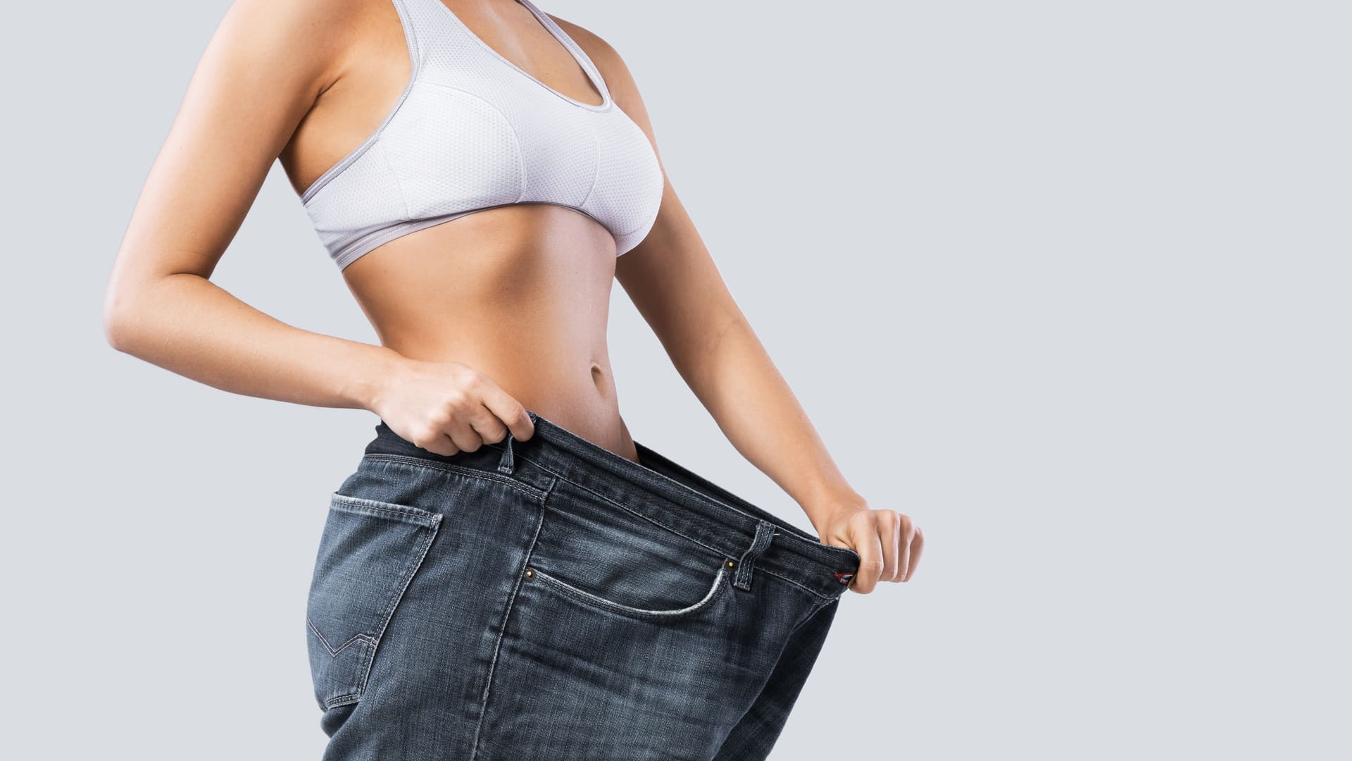 woman-showing-result-after-semiglutide-weight-loss-wearing-old-jeans