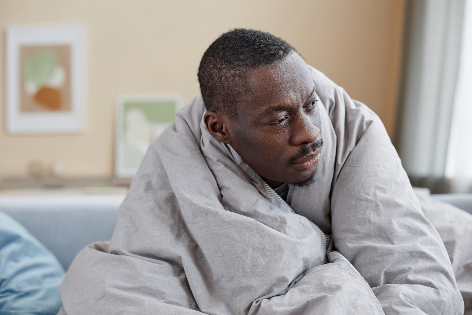 African American man wrapped in blankets struggling with depression